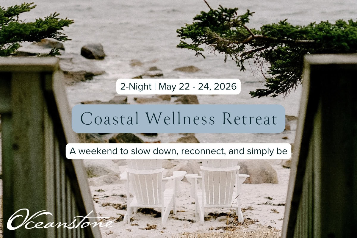 Two white Adirondack chairs overlook a tranquil, rocky shore at Oceanstone Resort, inviting calm reflection amid pine and wood.