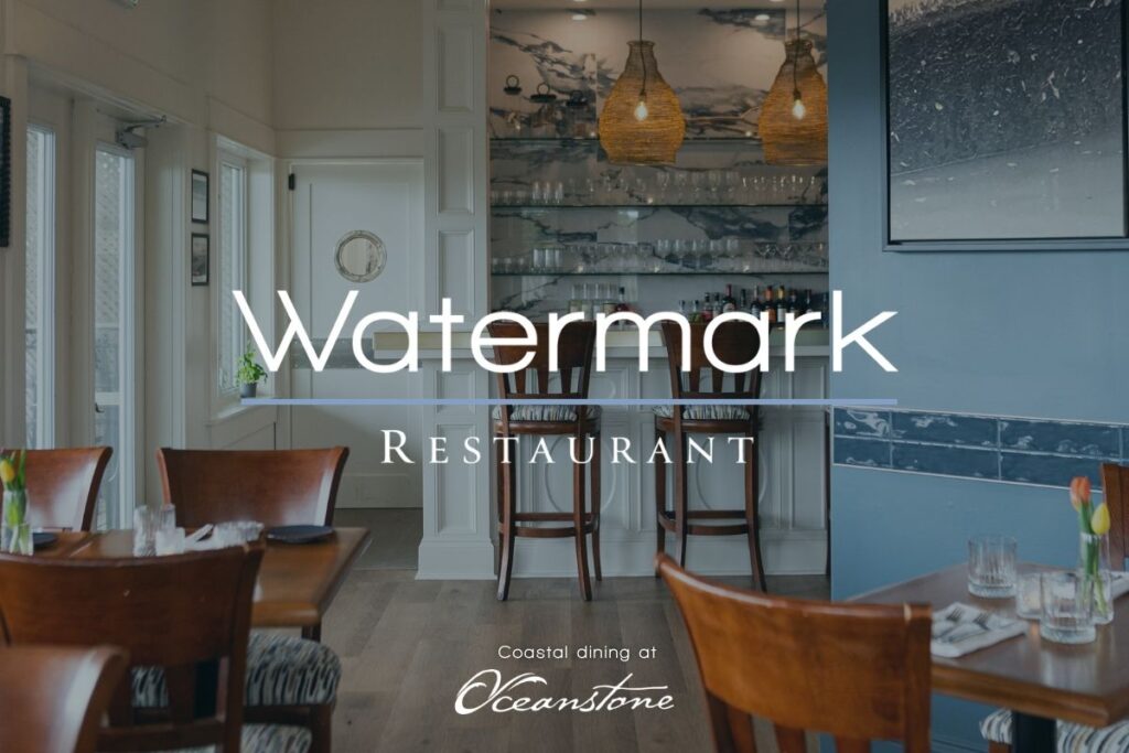 A tranquil restaurant interior at Oceanstone Resort and Spa features warmly lit wooden tables ready for guests, wicker pendant lights casting a gentle glow, a soothing marble-patterned wall, and expansive windows inviting in natural light. The words “Watermark Restaurant. Coastal dining at Oceanstone.” appear over the scene. Experience the serene ambiance of Watermark Restaurant’s grand opening, where every detail is designed for peaceful and rejuvenating coastal dining moments.